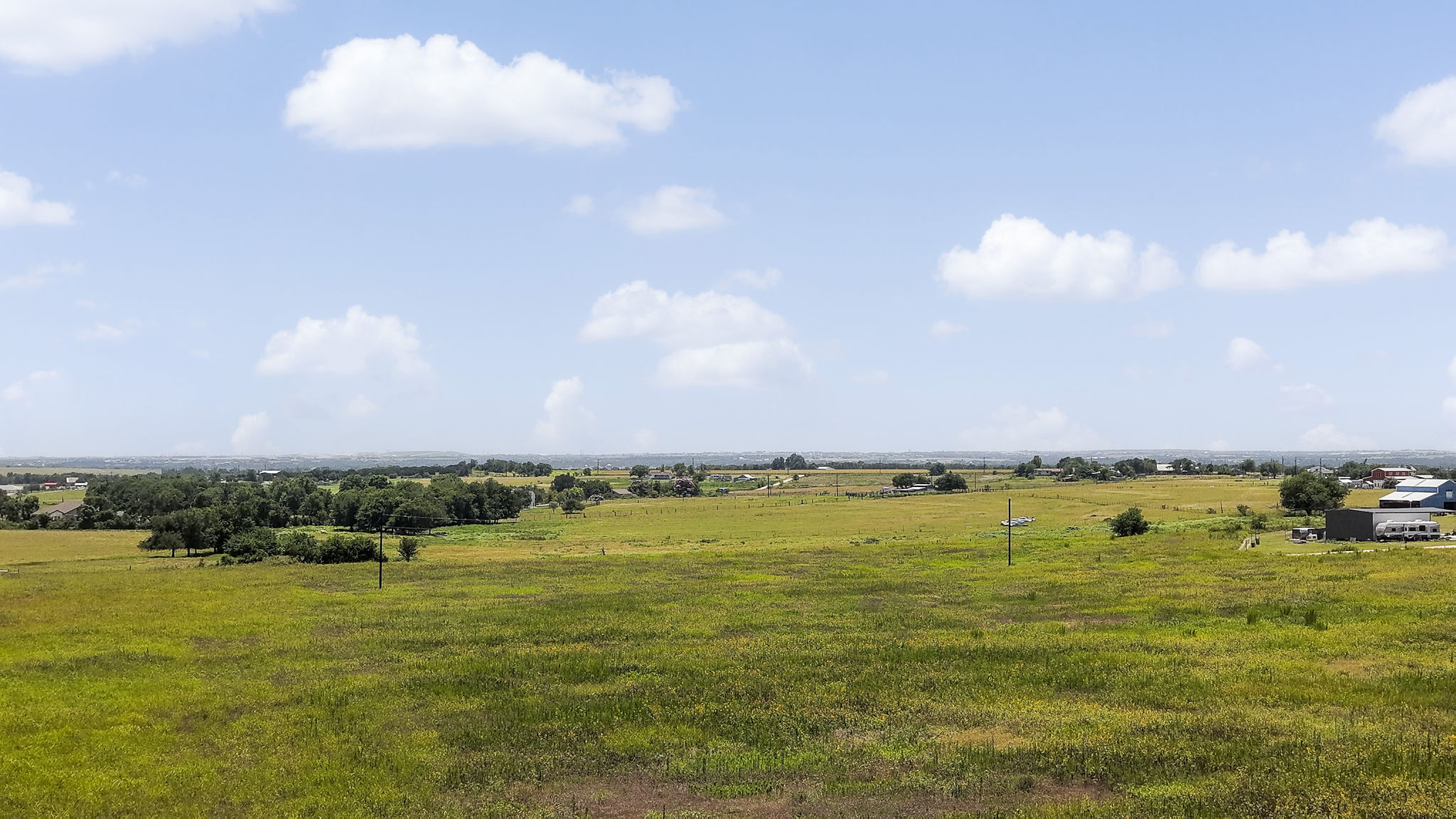 A vast, verdant pasture unfolds under an expansive sky, inviting agricultural pursuits.