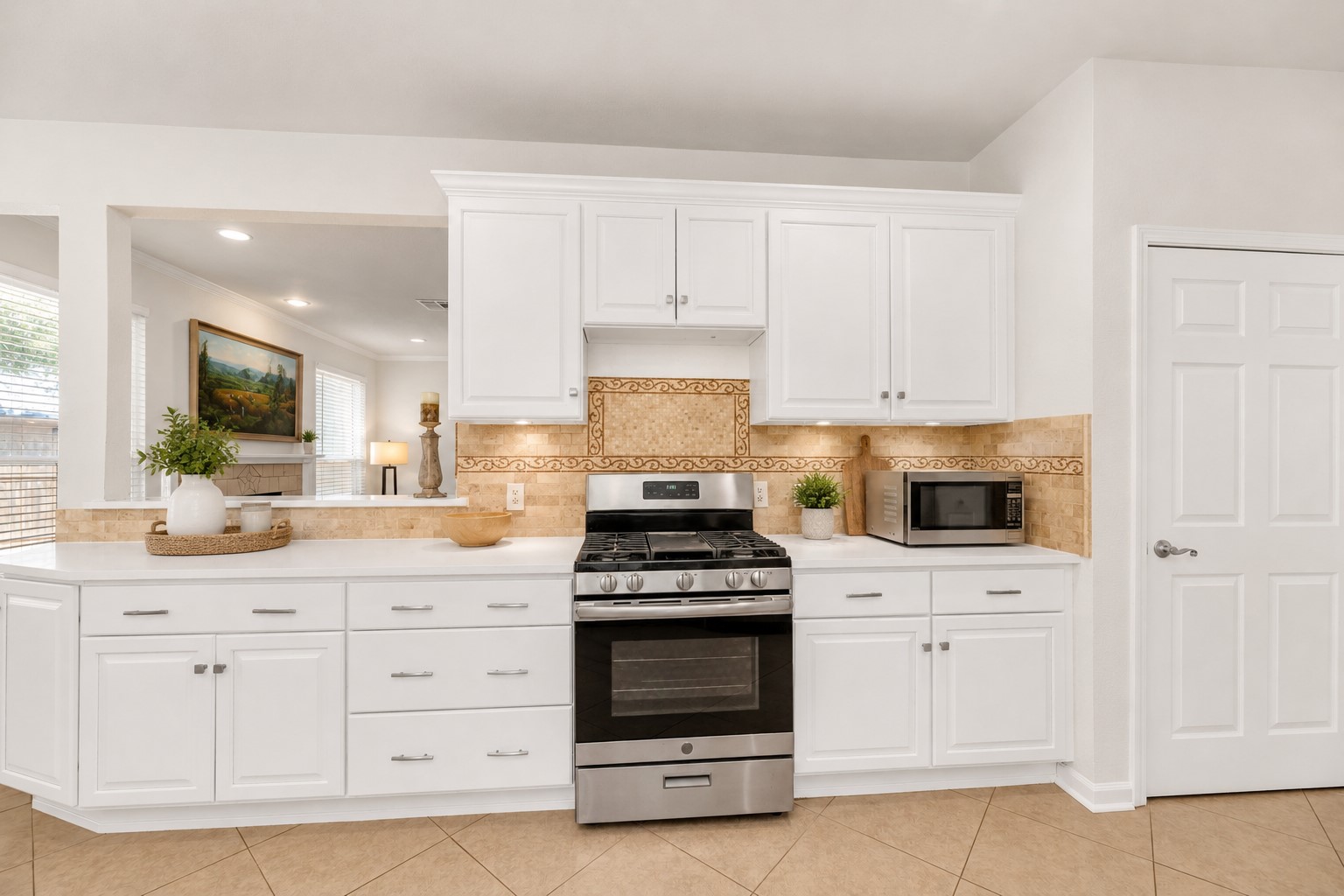 12528 Labrador Cove Austin, TX 78729 - Photo 17 of 40 Virtually Staged | Gourmet Kitchen | Designed to showcase both style and function, this beautifully appointed kitchen features crisp white cabinetry, stainless steel appliances, abundant storage, generous prep space, and an elegant designer tile backsplash. Soft Pottery Barn-inspired staging with natural wood accents, fresh greenery, layered textures, and warm neutral décor creates an inviting atmosphere while highlighting the kitchen’s spacious layout and timeless appeal. The open serving bar seamlessly connects to the living areas, making this space ideal for everyday living, casual dining, and effortless entertaining. Virtual staging is for illustrative purposes only.