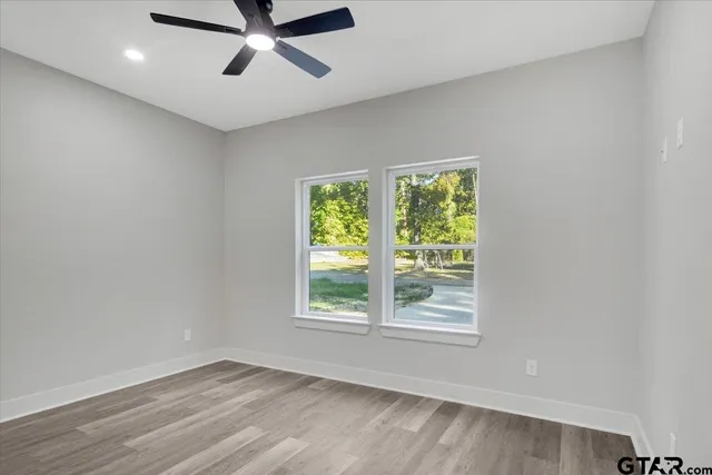 a view of a big room with wooden floor and windows