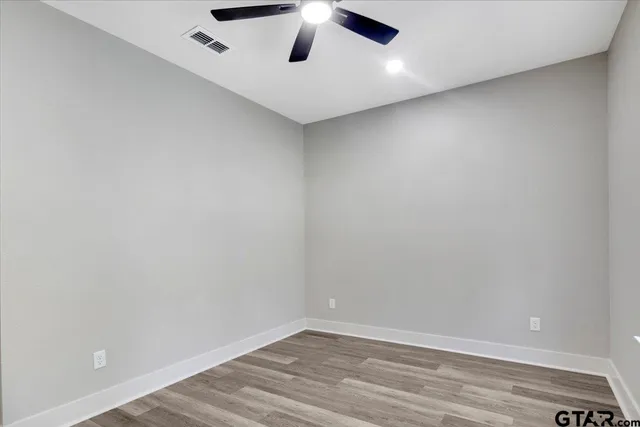 an empty room with a ceiling fan and wooden floor