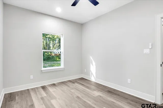 an empty room with a window and a ceiling fan
