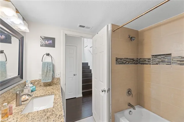 a bathroom with a granite countertop sink a toilet a mirror a bathtub and shower