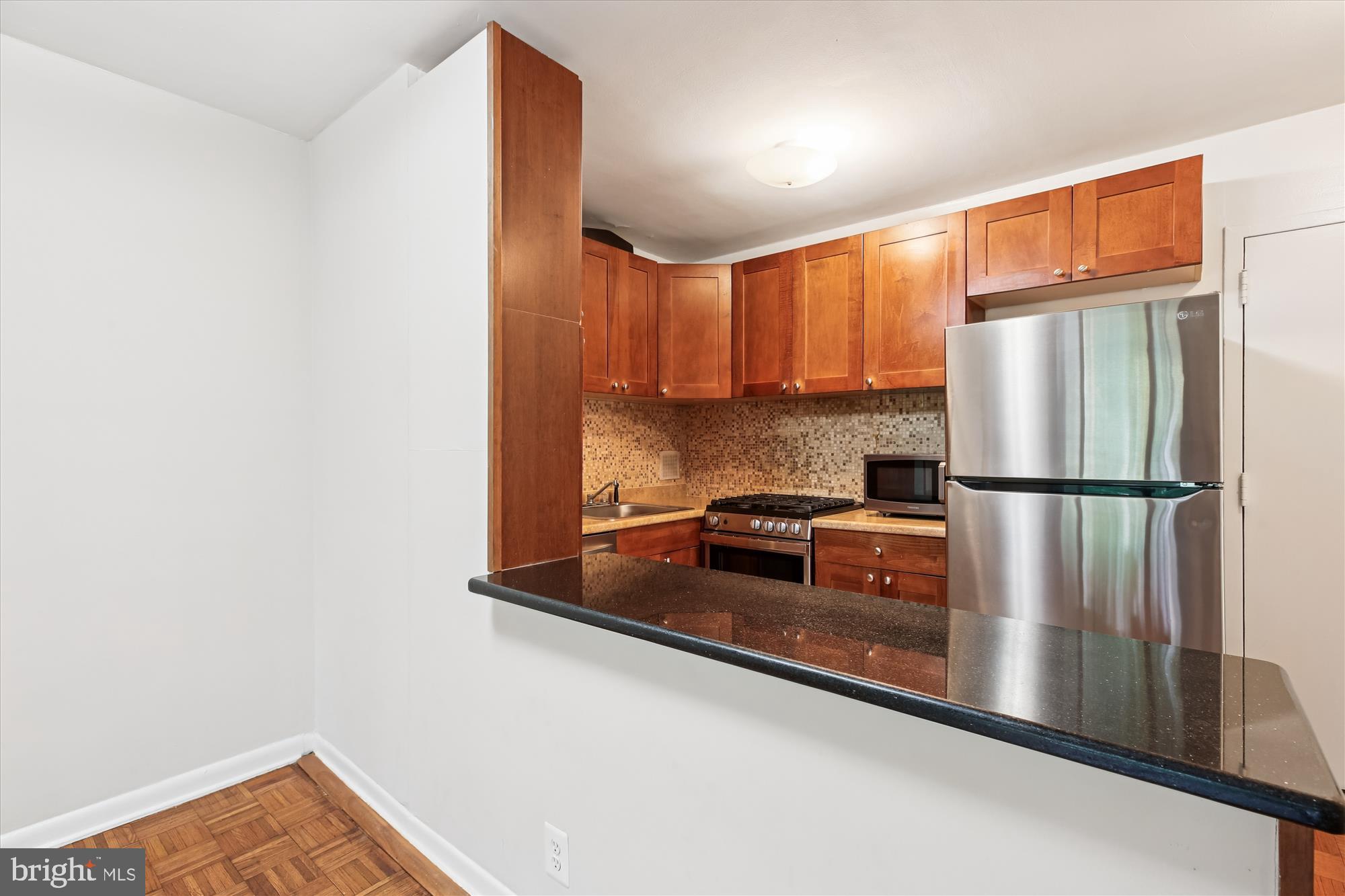 950 25th Street Northwest, Unit 709N Washington, DC 20037 - Photo 13 of 52 a kitchen with stainless steel appliances granite countertop a refrigerator a stove and a sink with wooden floor