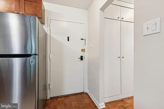 a view of a refrigerator in kitchen and an empty room