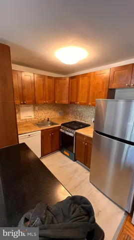 a kitchen with stainless steel appliances granite countertop a refrigerator a stove and a sink