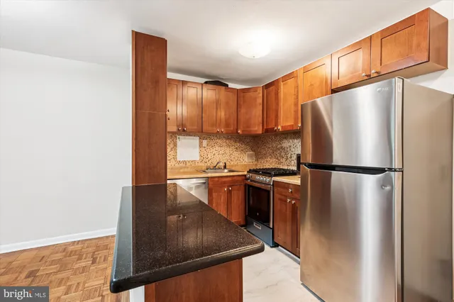 a kitchen with stainless steel appliances granite countertop a refrigerator a sink and a stove