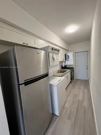 a kitchen with a refrigerator a stove top oven and wooden floor