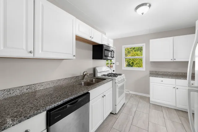 a kitchen with granite countertop a sink stove and cabinets