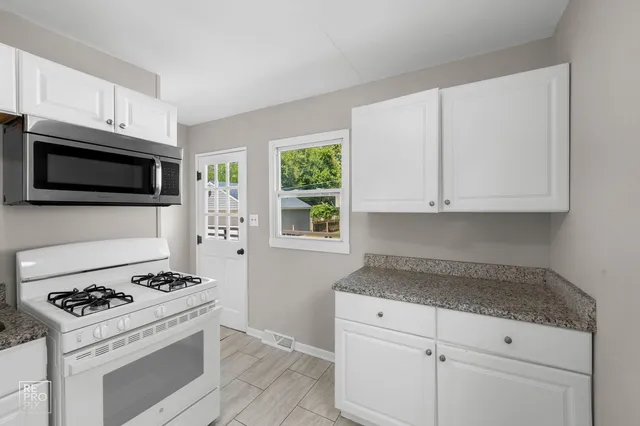 a kitchen with granite countertop white cabinets and appliances