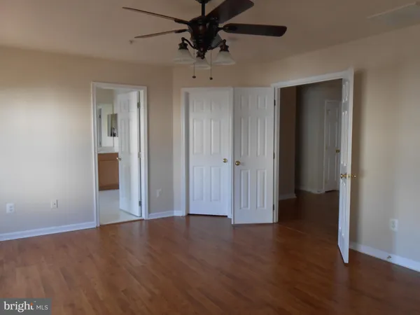 an empty room with wooden floor closet and windows