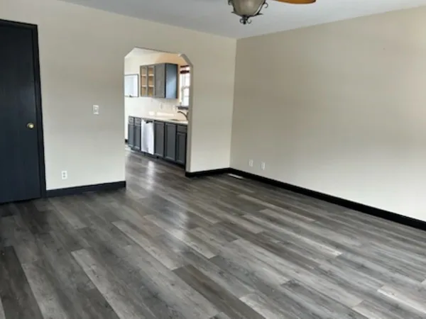 a view of kitchen and empty room with wooden floor