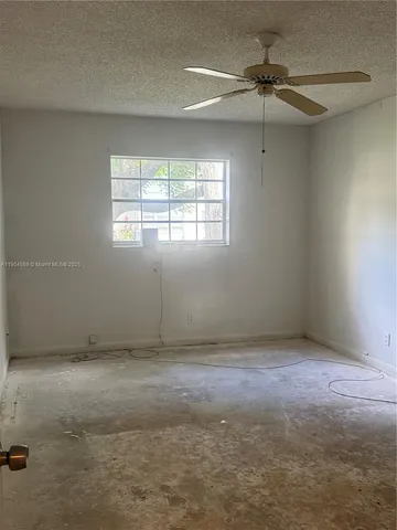 an empty room with windows and ceiling fan