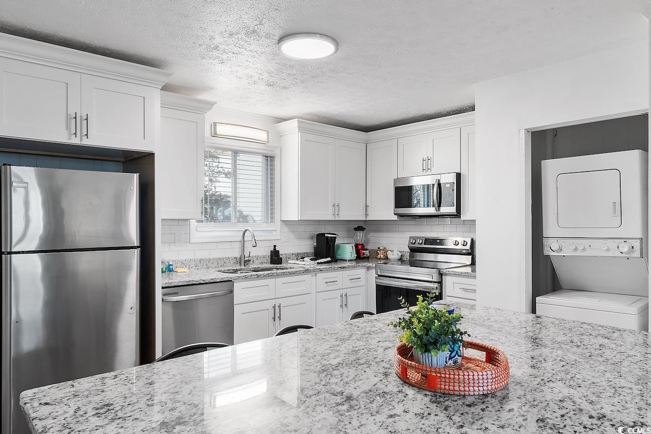 409 17th Avenue North, Unit 4 Myrtle Beach, SC 29577 - Photo 14 of 22 Kitchen with appliances with stainless steel finishes, light stone counters, a textured ceiling, and tasteful backsplash