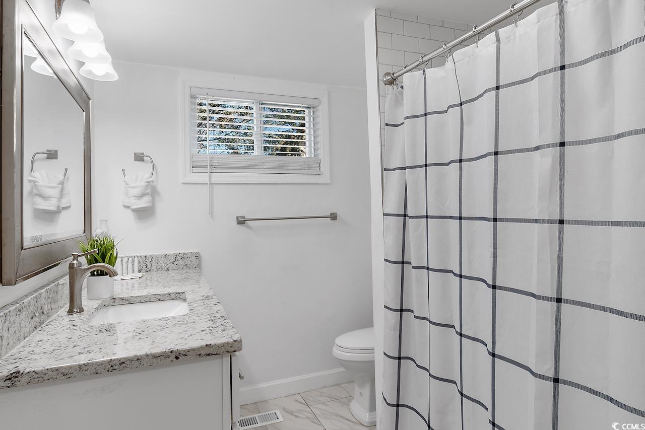 409 17th Avenue North, Unit 4 Myrtle Beach, SC 29577 - Photo 15 of 22 Full bathroom with vanity, light marble finish flooring, and curtained shower