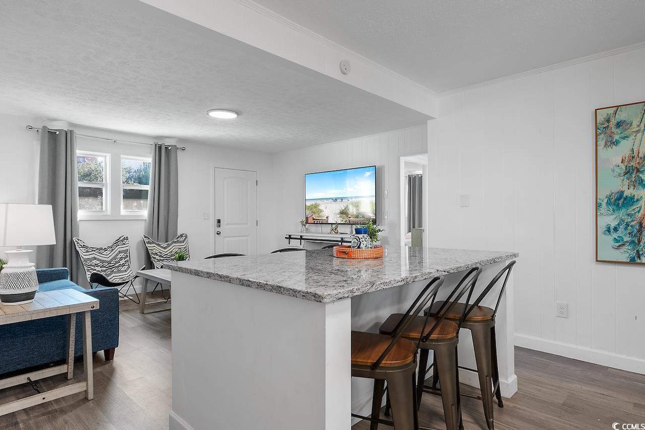 409 17th Avenue North, Unit 4 Myrtle Beach, SC 29577 - Photo 10 of 22 Kitchen with dark wood-style floors, a kitchen bar, light stone countertops, and a textured ceiling