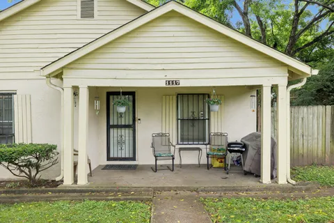 a view of a white house with lawn chairs and a large window