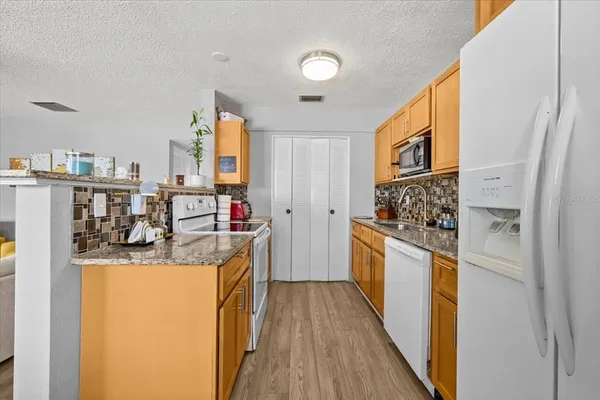 a kitchen with stainless steel appliances granite countertop a sink and wooden cabinets