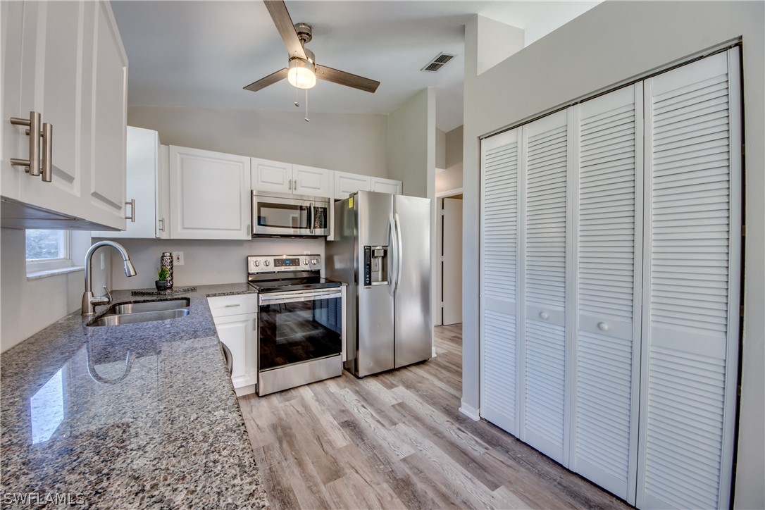 18372 Hawthorne Road Fort Myers, FL 33967 - Photo 5 of 28 a kitchen with stainless steel appliances granite countertop a refrigerator a stove and a sink with wooden floor