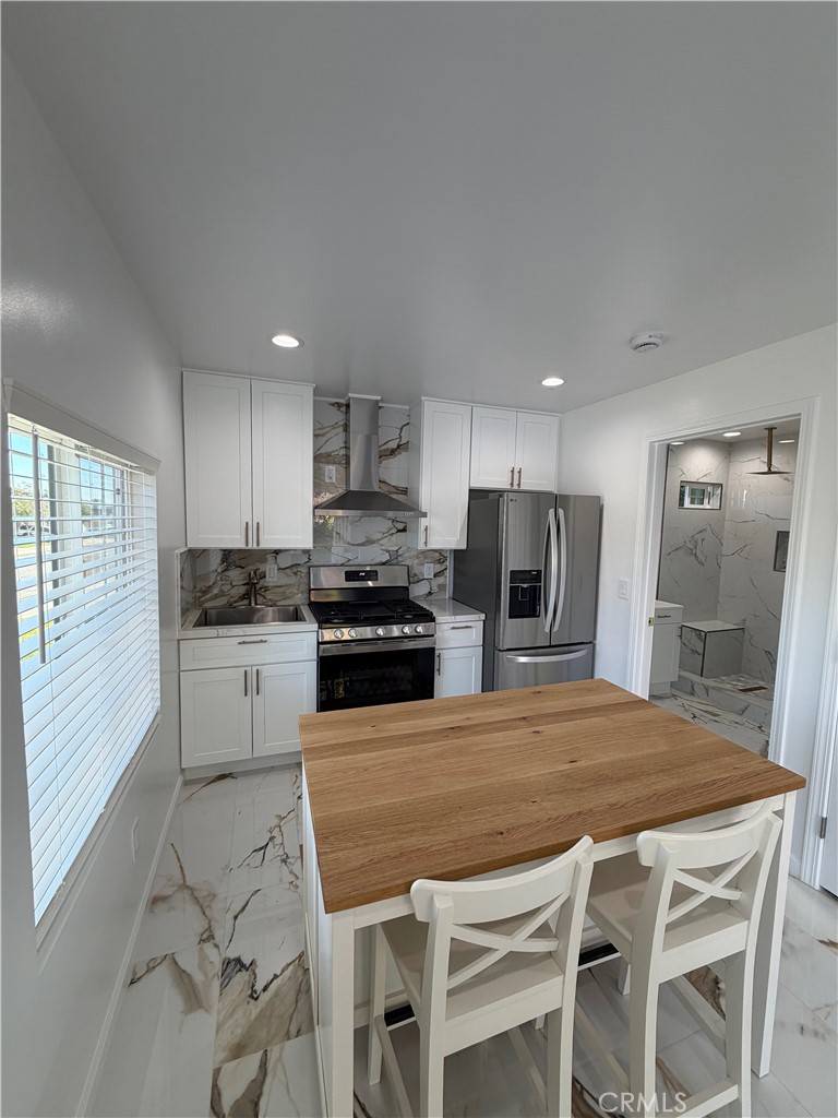 a kitchen with stainless steel appliances a stove a sink a refrigerator white cabinets and wooden floor