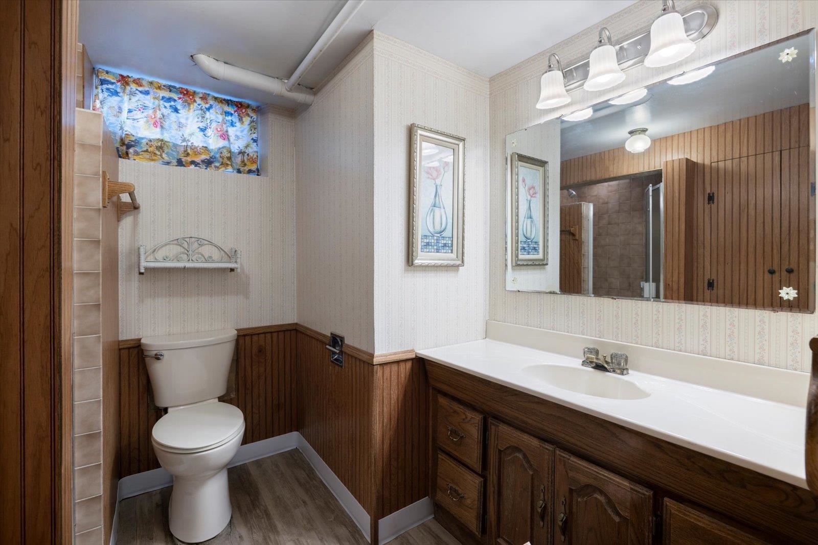 502 North Inner Drive Hibbing, MN 55746 - Photo 37 of 57 Full bath featuring wallpapered walls, vanity, a tile shower, light wood finished floors, and a wainscoted wall