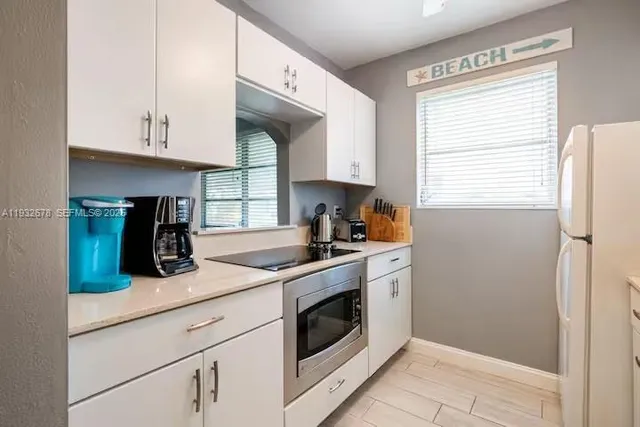 a kitchen with a white cabinets and window