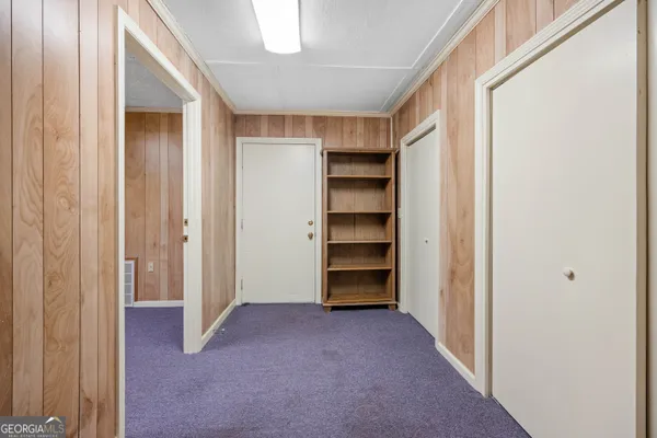 an empty room with a chandelier fan and closet