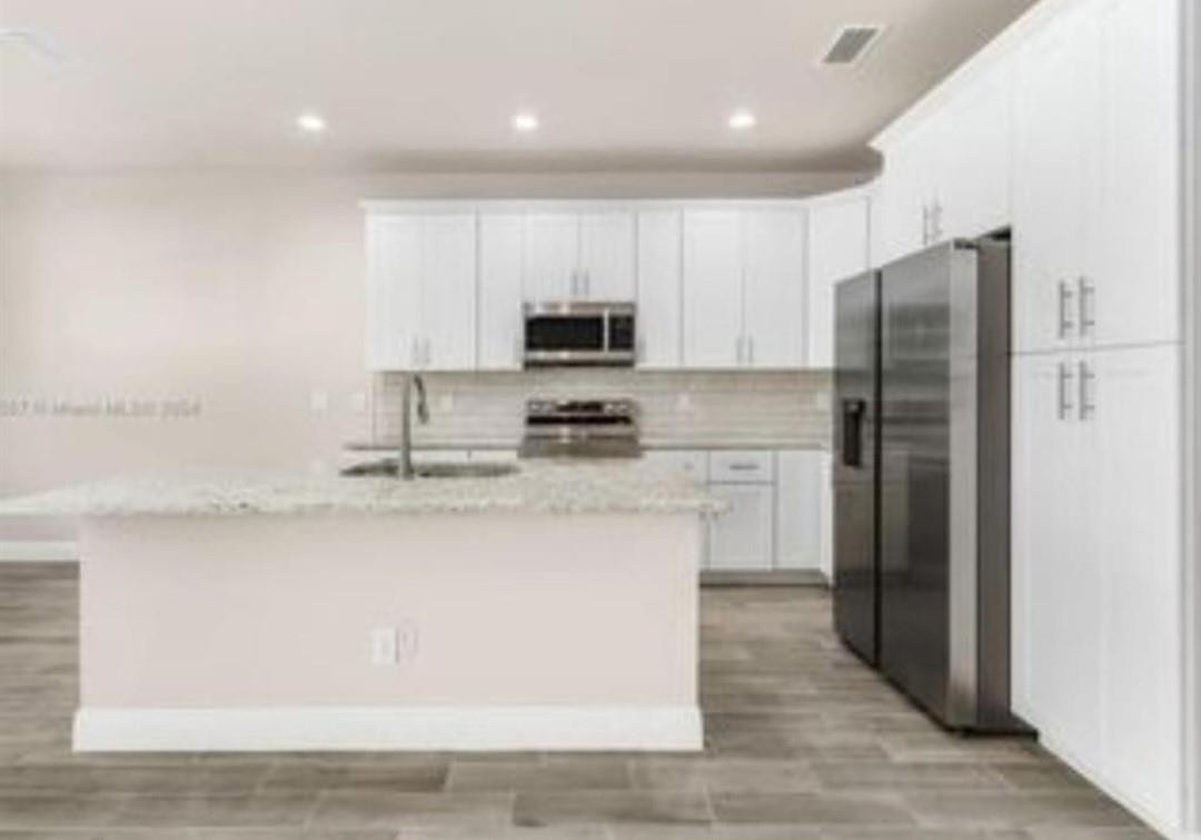 321 Neighborly Road LaBelle, FL 33935 - Photo 4 of 18 a kitchen with a refrigerator a stove top oven a sink and cabinets