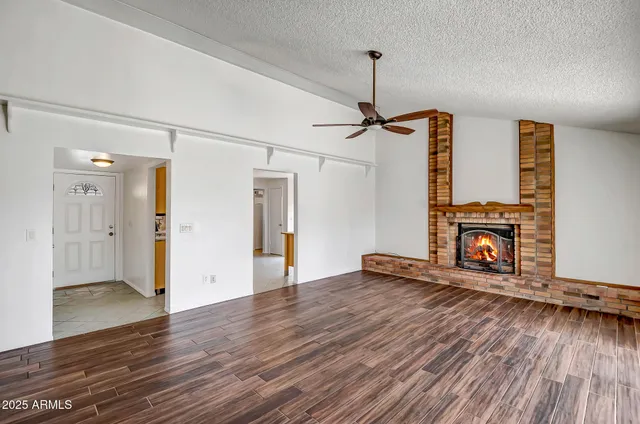a view of an empty room with wooden floor fireplace and a window