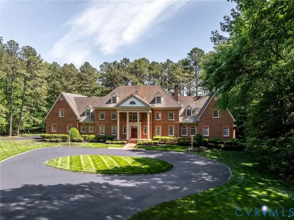 a view of a house with a big yard plants and large trees