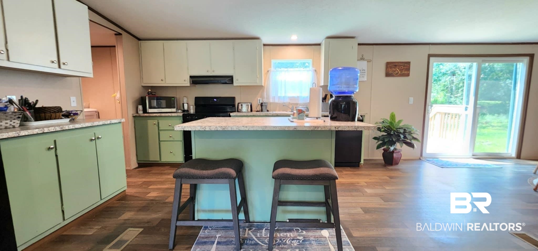 25474 Waterworld Road Robertsdale, AL 36567 - Photo 12 of 30 Kitchen with green cabinetry, light countertops, dark wood-style floors, a kitchen bar, and under cabinet range hood
