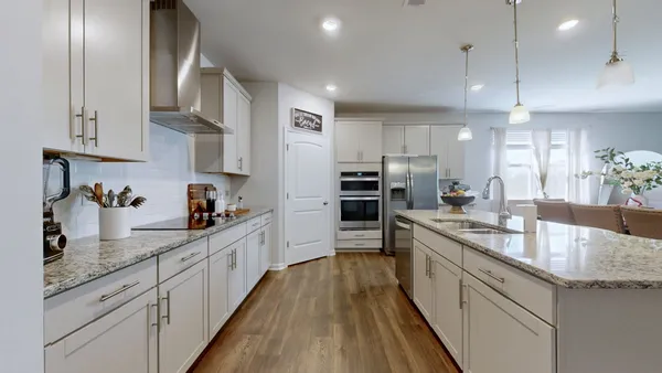 a large kitchen with granite countertop lots of counter space and wooden floor