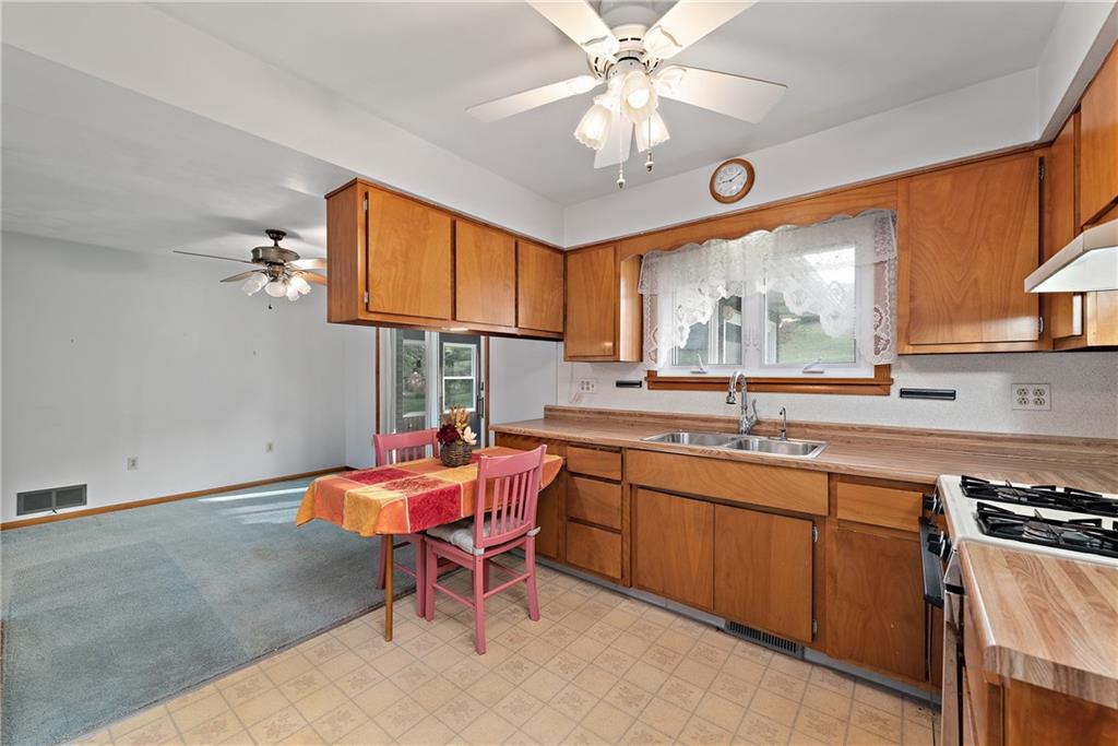 604 Davidson Drive Rochester, PA 15074 - Photo 14 of 25 a kitchen with stainless steel appliances granite countertop a sink dishwasher a stove a dining table and chairs with wooden floor