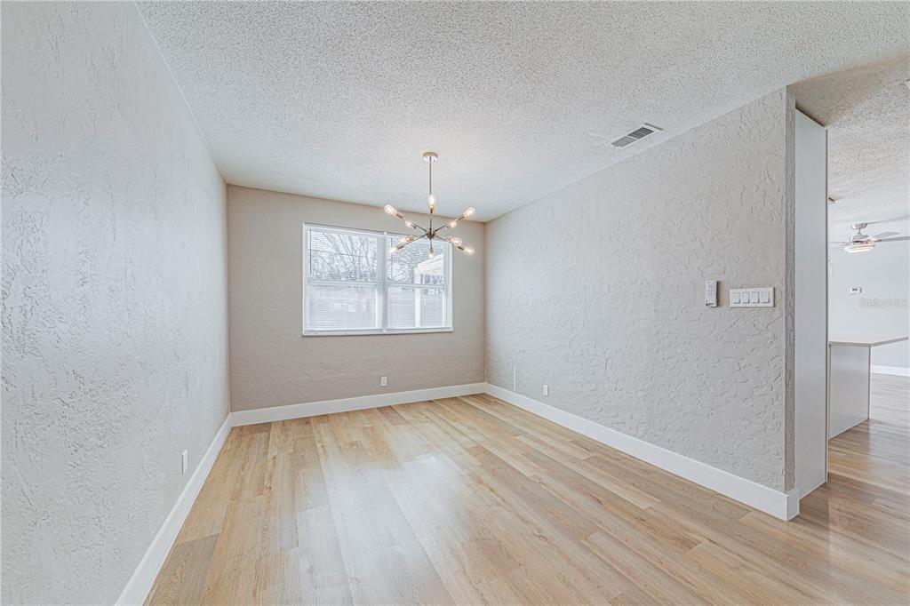 1648 Caldwell Road Daytona Beach, FL 32119 - Photo 16 of 45 an empty room with wooden floor chandelier and windows
