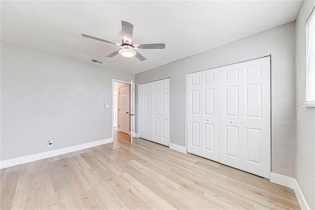 1648 Caldwell Road Daytona Beach, FL 32119 - Photo 24 of 45 an empty room with wooden floor ceiling fan and windows