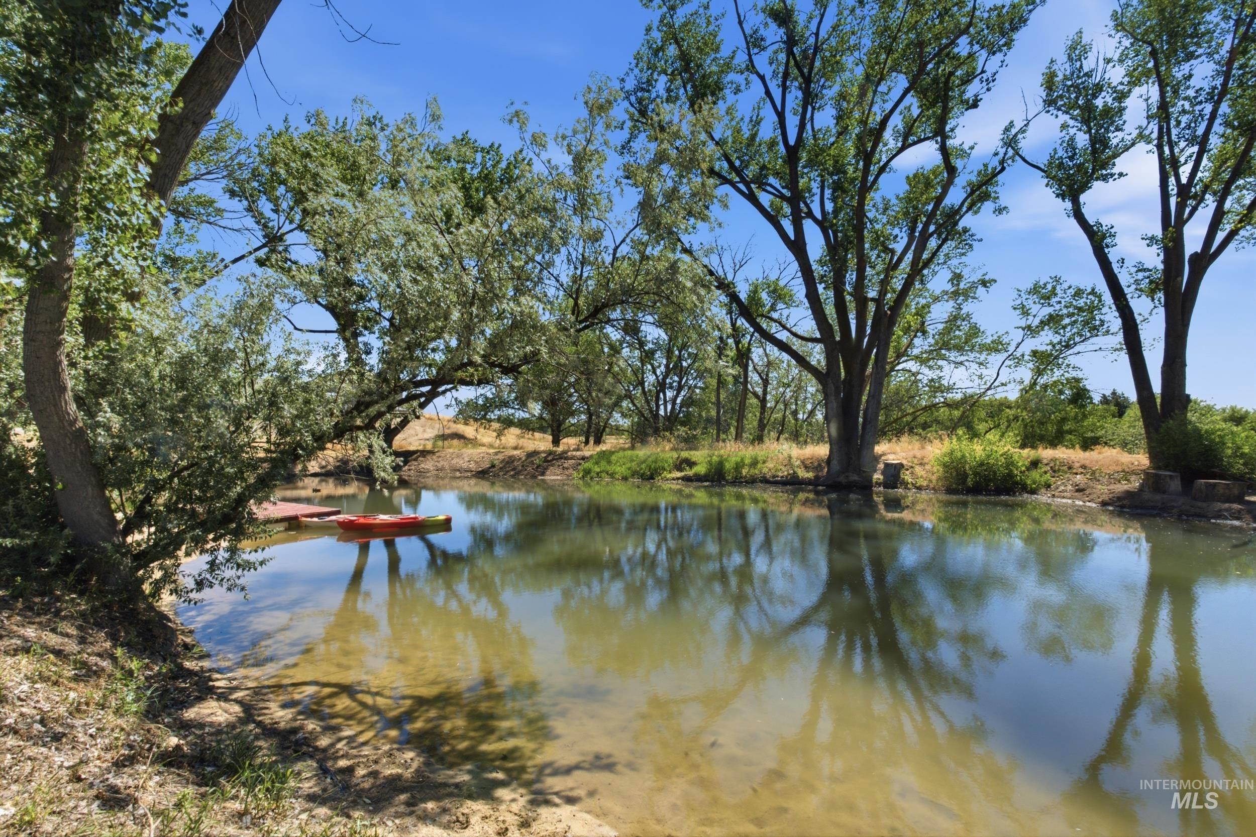 7781 Redmon Road Caldwell, ID 83607 - Photo 4 of 50 Private pond with a floating dock, natural sand bank, concrete steps, and mature surrounding trees