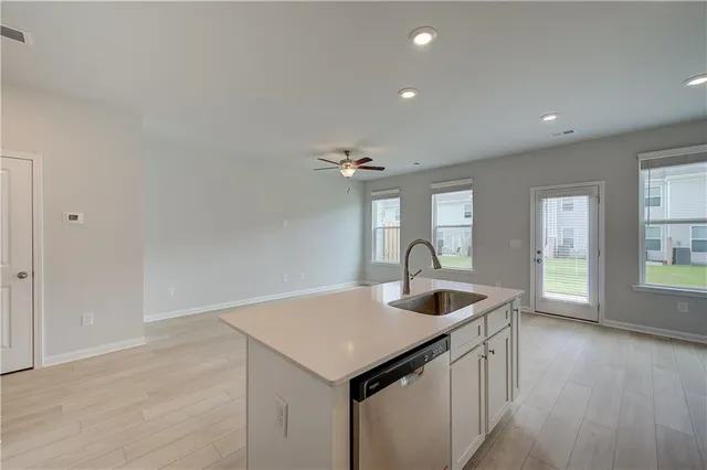 an empty room with wooden floor ceiling fan and windows