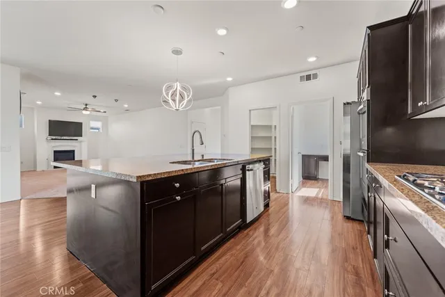 a kitchen with stainless steel appliances granite countertop a refrigerator a sink dishwasher a stove and a oven with wooden floor