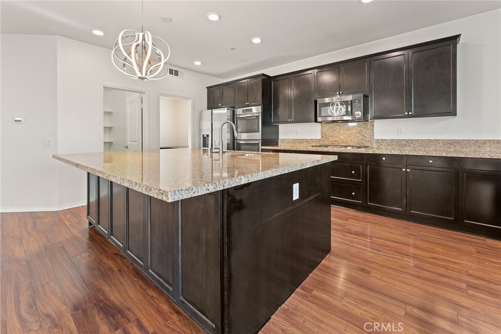 8022-8022 Sea Salt Avenue Fontana, CA 92336 - Photo 12 of 35 a kitchen with stainless steel appliances granite countertop a sink stove and wooden floor