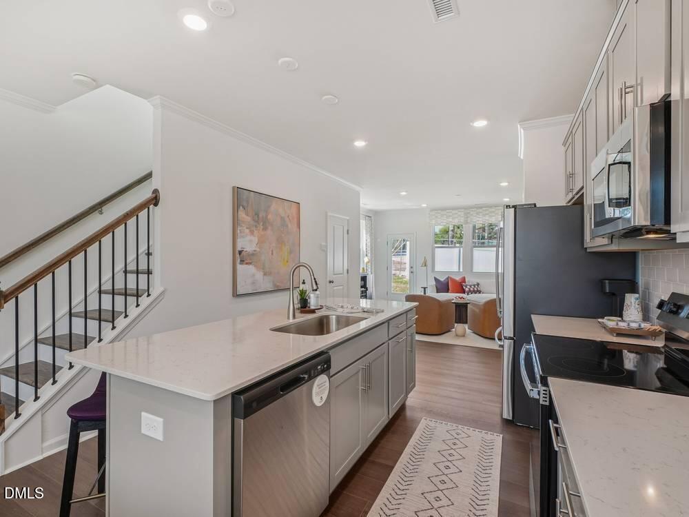3101 White Blossom Court, Unit SAVANNAH 3109 Raleigh, NC 27610 - Photo 3 of 20 a large kitchen with stainless steel appliances a sink a stove and a refrigerator