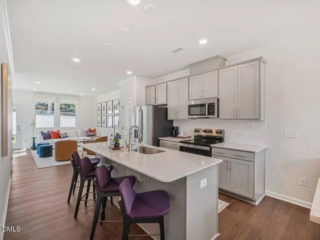 a kitchen that has a sink stainless steel appliances a refrigerator cabinets and wooden floor