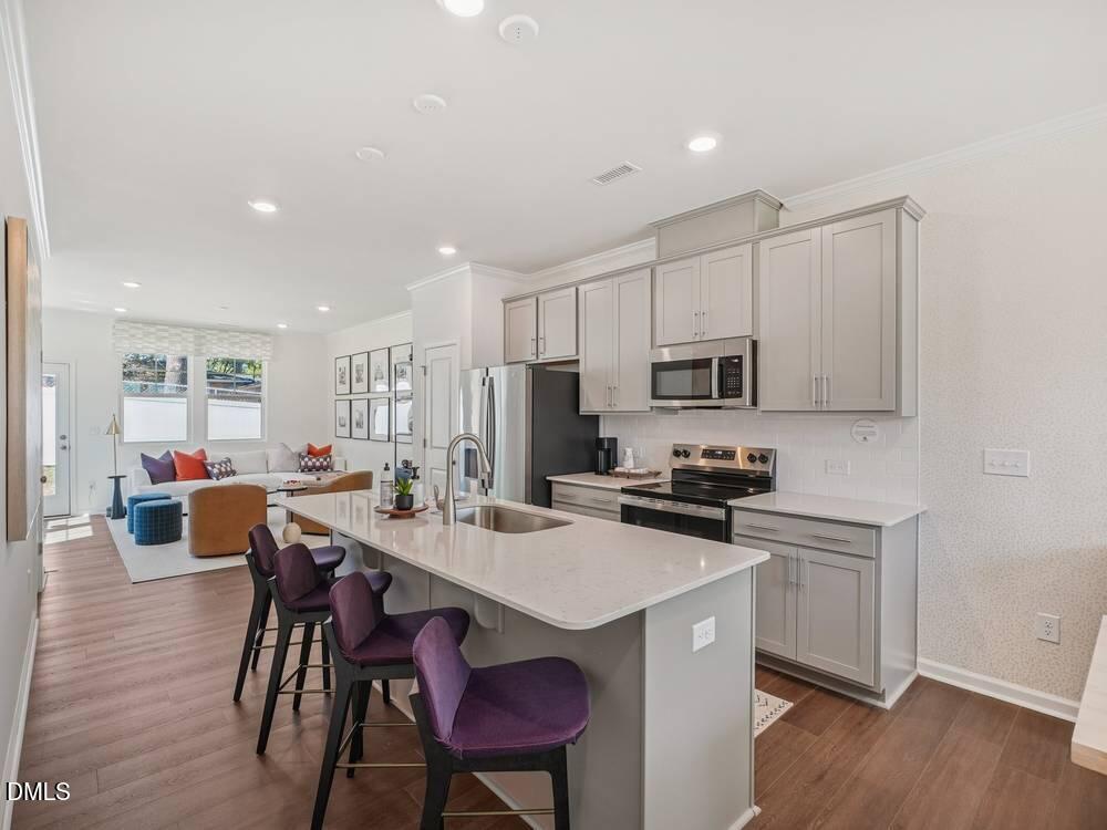 3101 White Blossom Court, Unit SAVANNAH 3109 Raleigh, NC 27610 - Photo 4 of 20 a kitchen with stainless steel appliances a sink a stove a refrigerator cabinets and chairs