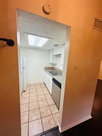 a kitchen with a sink a stove top oven and white cabinets