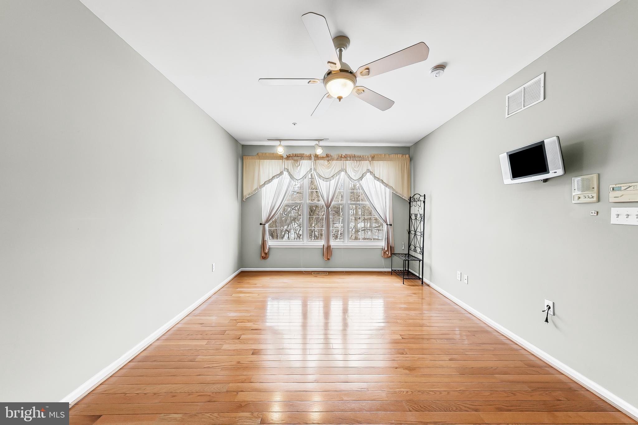 1299 Country Club Drive Springfield, PA 19064 - Photo 23 of 33 an empty room with wooden floor chandelier fan and windows