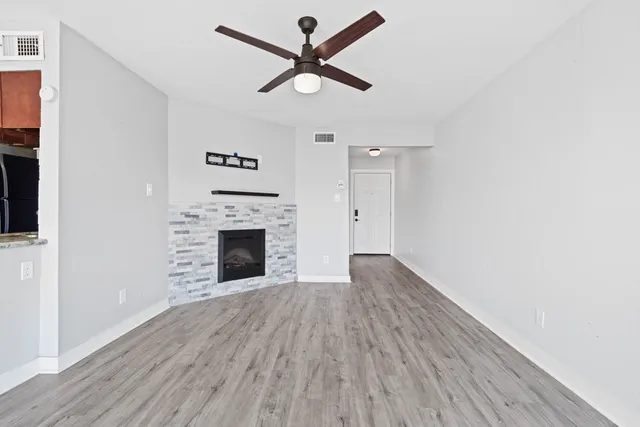 an empty room with wooden floor a ceiling fan and fireplace