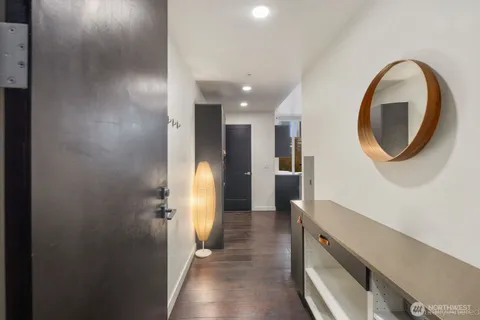 a view of a hallway with wooden floor and a bathroom