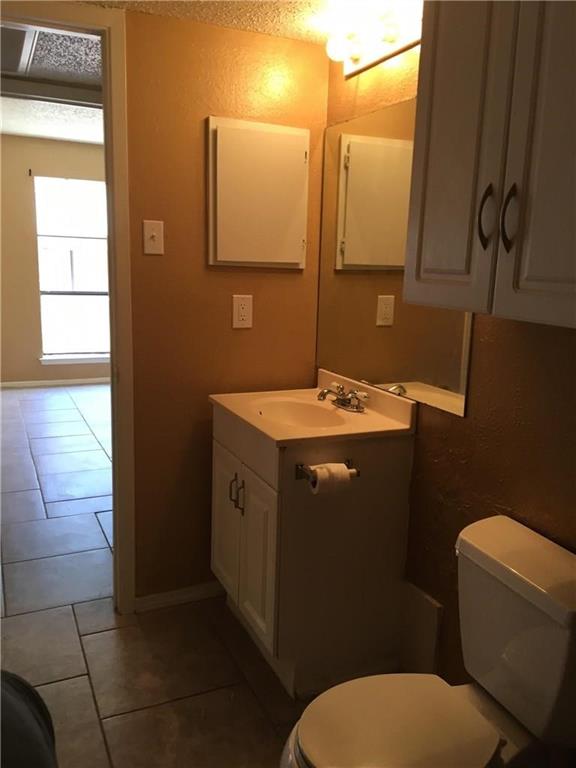 8110 Skillman Street, Unit 2020 Dallas, TX 75231 - Photo 7 of 12 Half bathroom featuring vanity, dark tile patterned floors, a textured ceiling, and a textured wall