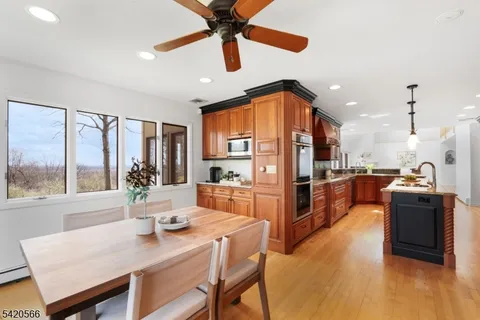 a kitchen with stainless steel appliances kitchen island granite countertop a refrigerator a stove a sink a dining table and chairs with wooden floor