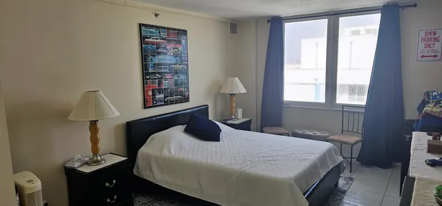 a bedroom with a bed and a lamp on dresser