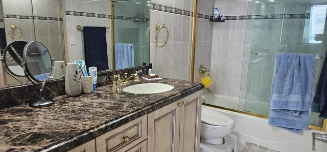 a bathroom with a granite countertop sink toilet and shower