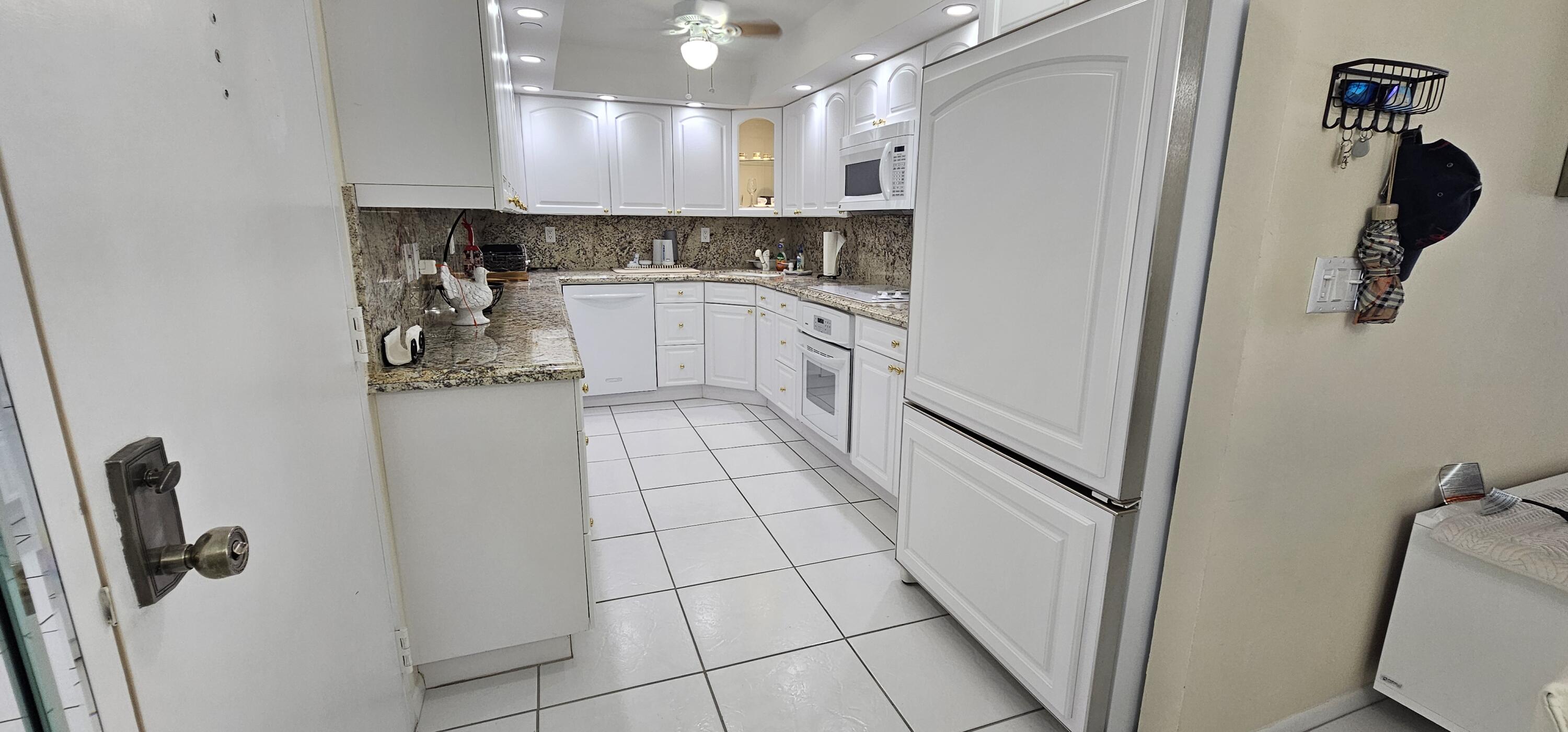 3215 South Ocean Boulevard, Unit 1010 Highland Beach, FL 33487 - Photo 6 of 23 a kitchen with white cabinets and white appliances